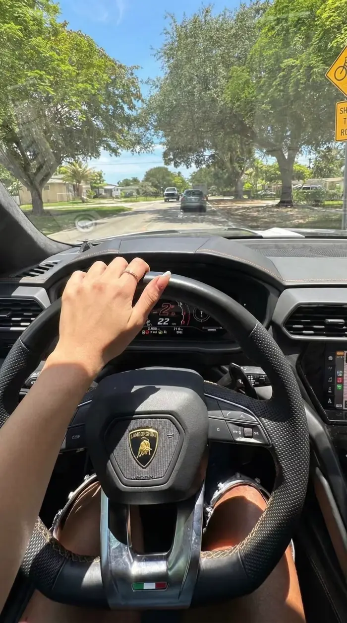 A hand on the steering wheel of a Lamborghini.